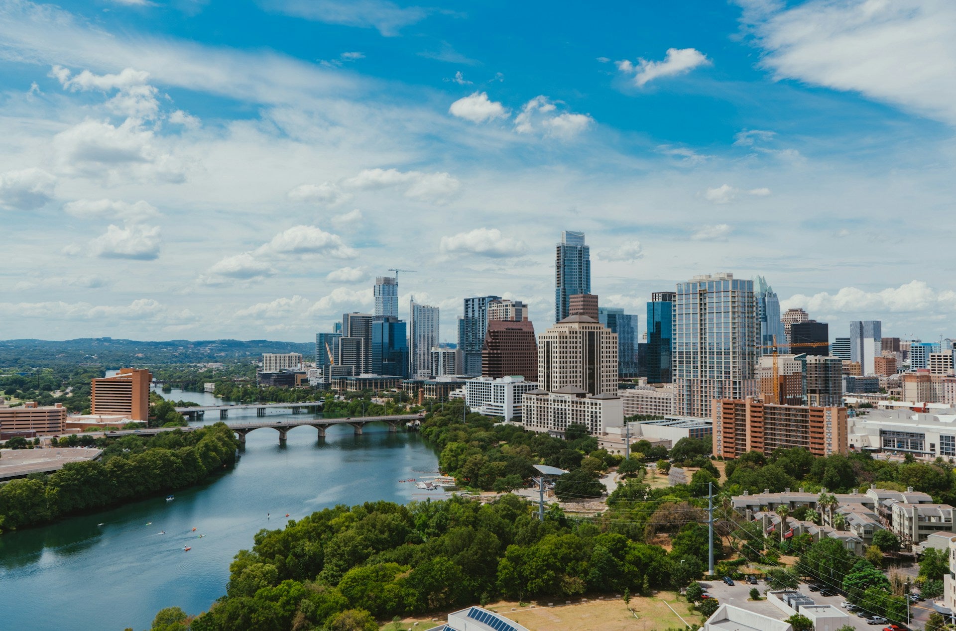 Dallas Fort Wroth city skyline with a river and greenery under a blue sky with clouds